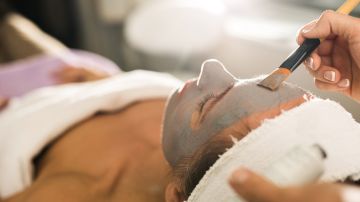 Close up of unrecognizable beautician applying clay mask on woman's face during beauty treatment. Photo by StockPlanets/ Getty Images