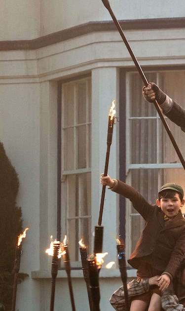 Jack (Lin-Manuel Miranda) Mary Poppins (Emily Blunt) and the Banks children with a crew of street lamplighters at 17 Cherry Tree Lane in 'Mary Poppins Returns.' Courtesy of Disney