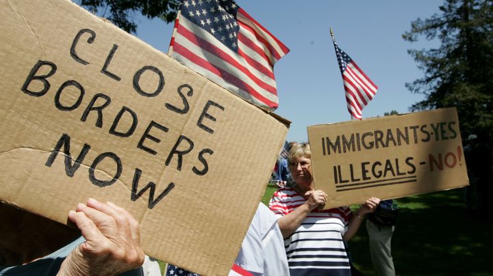 Anti-immigration demonstrators hold signs and American flags during an anti-immigration rally. Photo by Justin Sullivan/Getty Images