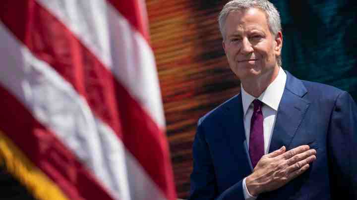 New York City Mayor Bill de Blasio stands for the Pledge of Allegiance during a dedication ceremony for the new Statue of Liberty Museum, May 16, 2019 on Liberty Island in New York City. De Blasio announced on Thursday morning that he is launching a campaign for the presidency. (Photo by Drew Angerer/Getty Images)