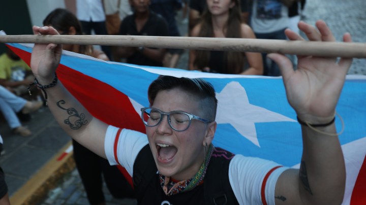 Nicole Lopez joins with other protesters demonstrating along a street leading to the Governors mansion as they call for Puerto Rican Governor Ricardo Rossello to step down on July 16, 2019 in Old San Juan, Puerto Rico. Photo by Joe Raedle/Getty Images