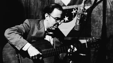 Brazilian singer and musician Joao Gilberto strums the guitar in front of a microphone during studio session. 1980s. Photo by Dario Zalis/Contexto/Getty Images
