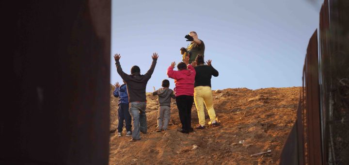 Members of the migrant caravan turn themselves in to a U.S. Border Patrol agent after climbing over the U.S.-Mexico border fence on December 3, 2018 while crossing into San Diego, CA from Tijuana, Mexico. Photo by John Moore/Getty Images