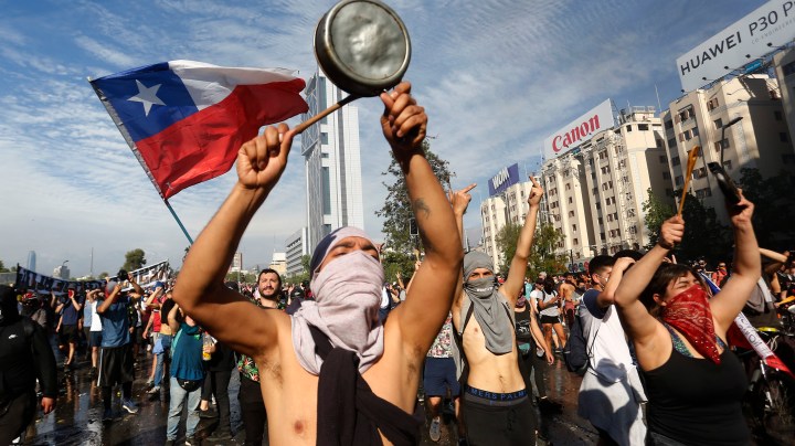 Demonstrators display flags and banners during a protest against President Sebastian Piñera on October 21, 2019 in Santiago, Chile. Photo by Marcelo Hernandez/Getty Images