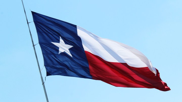 Texas flag waves amid blue sky. Photo by Mary Delgado / EyeEm / Getty Images