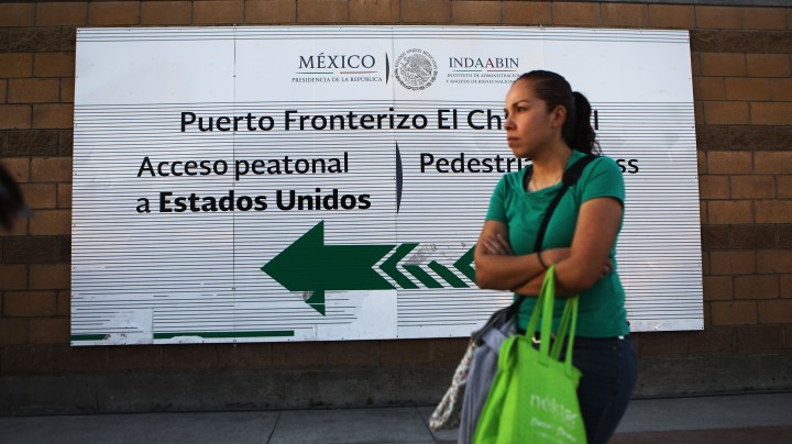 A woman stands at the El Chapparal port of entry, with a sign pointing toward the U.S., on January 25, 2019 in Tijuana, Mexico. Photo by Mario Tama/Getty Images