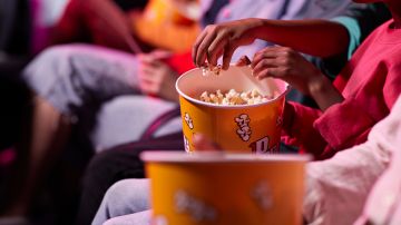 Friends sharing popcorn in theater. Getty Images
