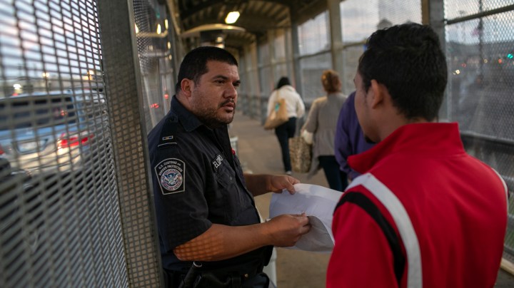 A U.S. Customs and Border Protection officer checks immigration documents as a Honduran asylum seeker arrives to the international bridge from Mexico to the United States on December 09, 2019 next to the border town of Matamoros, Mexico. Photo by John Moore/Getty Images