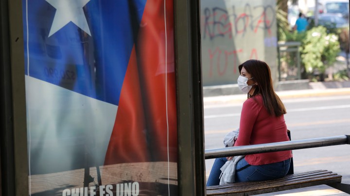 A commuter waits for the bus during the coronavirus pandemic on March 20, 2020 in Santiago, Chile. Photo by Marcelo Hernandez/Getty Images