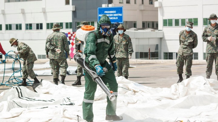 A worker using a mask and a work suit cleans near the mobile emergency unit donated by the Red Cross to Guayaquil at the IESS hospital in Los Ceibos on April 7, 2020 in Guayaquil, Ecuador. Photo by Eduardo Maquilón/Getty Images
