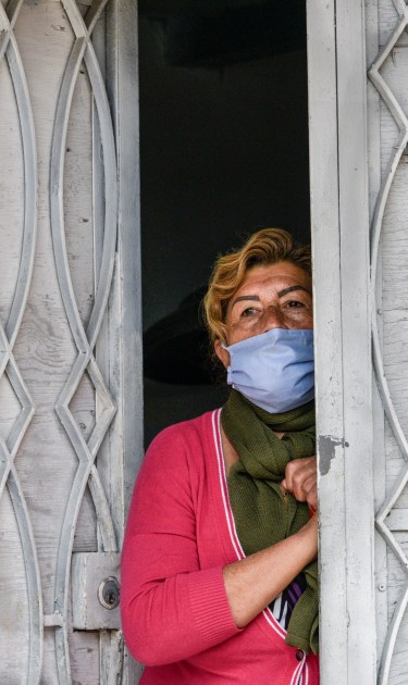 A woman wearing a face mask waits at the door of her house to receive food aid as Colombian military visit the impoverished slum at El Codito neighbourhood  handing out family food baskets during government-ordered obligatory quarantine on April 23, 2020 in Bogota, Colombia. Photo by Guillermo Legaria/Getty Images