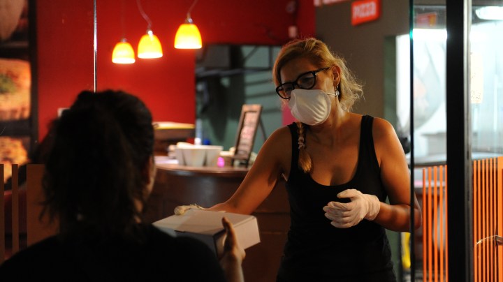A delivery girl picks up an order at a pizza restaurant on March 26, 2020 in Santa Fe, Argentina. Photo by José Almeida/Getty Images