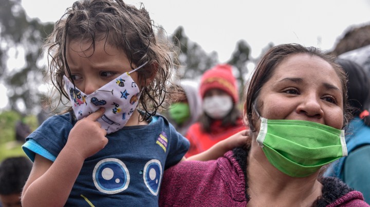 A woman holds her daughter while she waits to receive food aid as Colombian military visit the El Codito neighborhood handing out family food baskets during government-ordered obligatory quarantine on April 23, 2020 in Bogota, Colombia. Photo by Guillermo Legaria/Getty Images