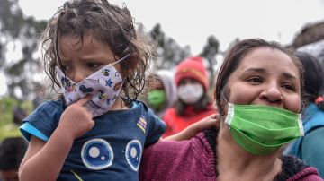 A woman holds her daughter while she waits to receive food aid as Colombian military visit the El Codito neighborhood handing out family food baskets during government-ordered obligatory quarantine on April 23, 2020 in Bogota, Colombia. Photo by Guillermo Legaria/Getty Images