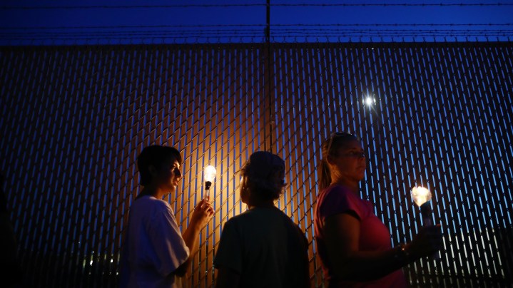 Activist Angel Ulloa (L) holds a candle at a vigil outside the Border Patrol station where lawyers reported that detained migrant children were held unbathed and hungry on June 25, 2019 in Clint, Texas. Photo by Mario Tama/Getty Images