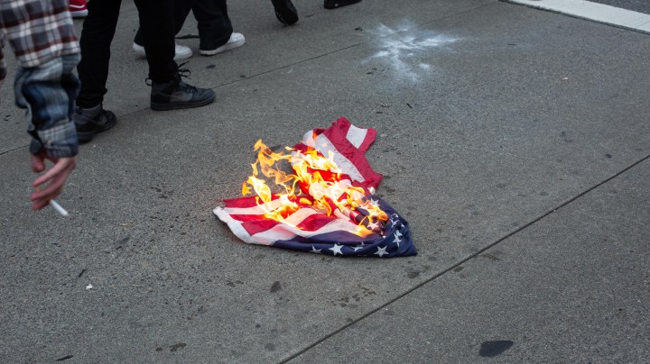 A U.S. flag burns outside of Bellevue Square Mall while looting takes place on May 31, 2020 in Bellevue, Washington. Protests due to the recent death of George Floyd took place in Bellevue in addition to Seattle, with looting in Bellevue and at least one burned automobile there. Photo by David Ryder/Getty Images