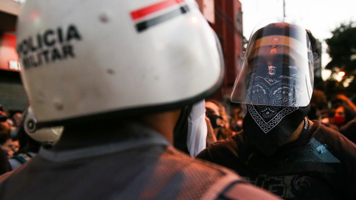 A protester wearing a face mask stare at a police officer during a protest amidst the coronavirus (COVID-19) pandemic on June 7, 2020 in Sao Paulo, Brazil. Photo by Alexandre Schneider/Getty Images