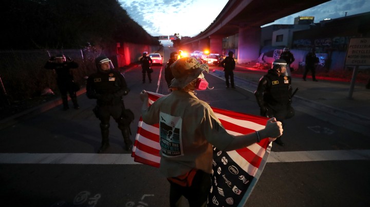 A demonstrator holds an American flag in front of California Highway Patrol officers during a protest sparked by the death of George Floyd while in police custody on May 29, 2020 in Oakland, California. Photo by Justin Sullivan/Getty Images