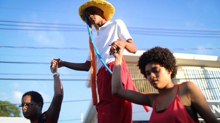 A teen (TOP) marches on stilts during a student Christmas parade on December 21, 2017 in Loiza, Puerto Rico. Photo by Mario Tama/Getty Images
