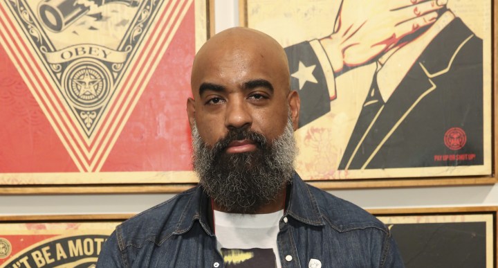 Artist Tony Peralta poses for a portrait in front of Shepard Fairey's artwork at The Dean Collection X BACARDI No Commission Art Fair. Photo by Monica Schipper/Getty Images for Bacardi