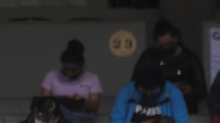 A staff member stands guard among students who take their UNAM admission exam while following the preventive measuress to avoid Covid-19 at Olimpico Universitario Stadium on August 19, 2020 in Mexico City, Mexico. Photo by Hector Vivas/Getty Images