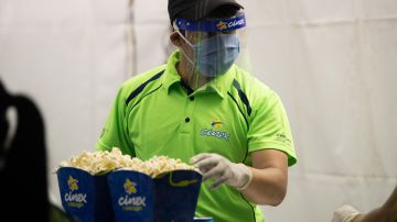 A drive-in employee distributes popcorn and sodas in the parking lot of the Metropolitan University on July 3, 2020 in Caracas, Venezuela. Photo by Carolina Cabral/Getty Images