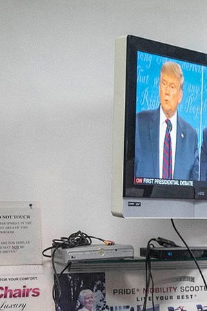A man laughs as he watches the first presidential debate in a store on U Street on September 29, 2020 in Washington, United States. Photo by Sarah Silbiger/Getty Images