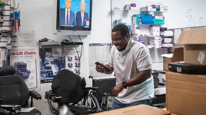 A man laughs as he watches the first presidential debate in a store on U Street on September 29, 2020 in Washington, United States. Photo by Sarah Silbiger/Getty Images