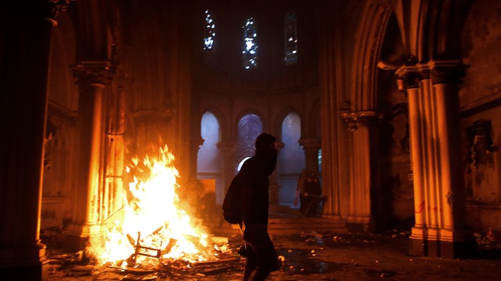 Masked men burn down a Carabineros church during a protest on October 18, 2020 in Santiago, Chile. Photo by Marcelo Hernandez/Getty Images