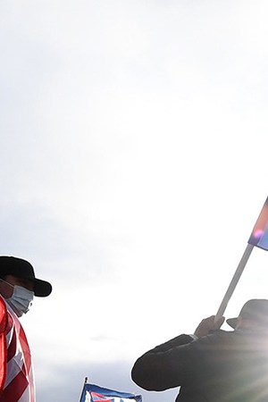 Daniel Briones (L) of Nevada carries an American flag as Chris Vela (C) of Nevada waves a Biden-Harris flag while other supporters of Joe Biden hold up a Mexican flag as they prepare to hold a car parade to celebrate the outcome of Tuesday's election on November 7, 2020 in Las Vegas, Nevada. Photo by Ethan Miller/Getty Images