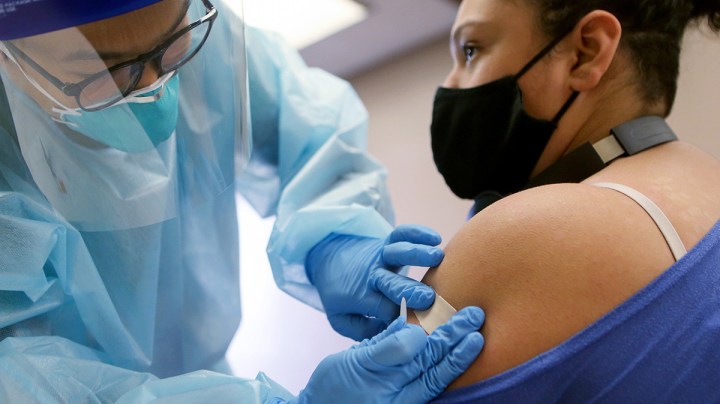 A nurse applies a band- aid after administering the flu vaccination shot to a woman at a free clinic held at a local library on October 14, 2020 in Lakewood, California. Photo by Mario Tama/Getty Images.