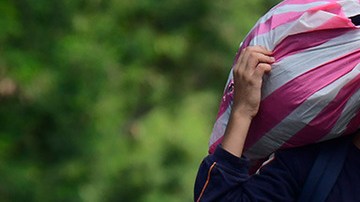 A young boy walks with a bag on his back on the streets flooded by the Tropical Storm Eta on November 8, 2020 in Rio Nance, Honduras. Photo by Yoseph Amaya/Getty Images