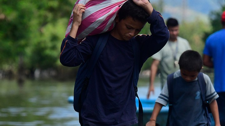 A young boy walks with a bag on his back on the streets flooded by the Tropical Storm Eta on November 8, 2020 in Rio Nance, Honduras. Photo by Yoseph Amaya/Getty Images