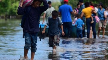 A young boy walks with a bag on his back on the streets flooded by the Tropical Storm Eta on November 8, 2020 in Rio Nance, Honduras. Photo by Yoseph Amaya/Getty Images