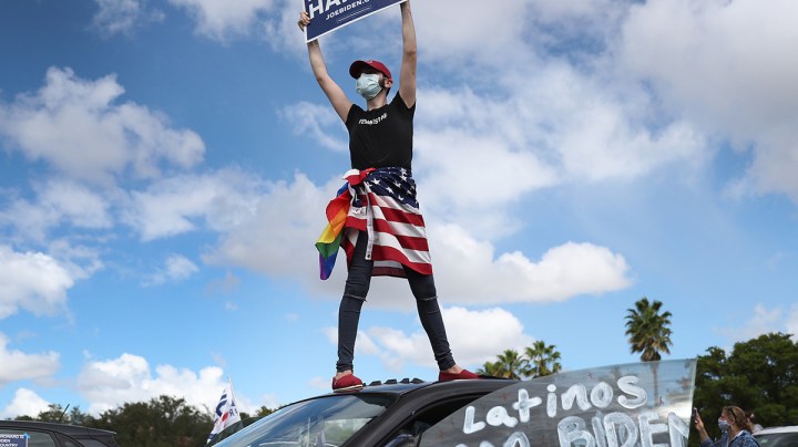 Marco Incer stands on the roof of his car as he shows support for Democratic presidential nominee Joe Biden during a Worker Caravan for Biden event on October 18, 2020 in Doral, Florida. Photo by Joe Raedle/Getty Images