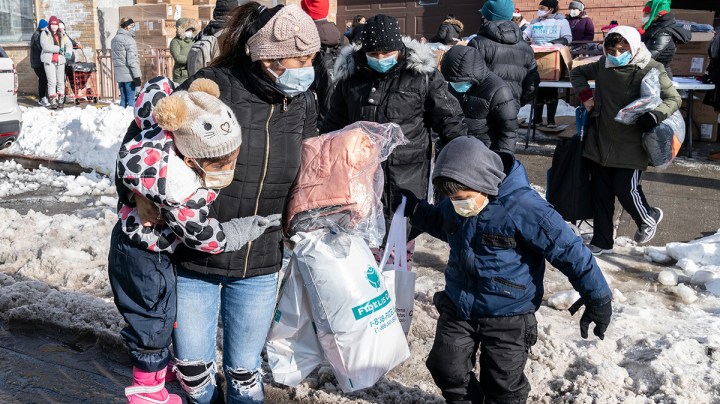 A mother and 2 kids received coats and toys during New York Cares volunteers in partnership with Together We Can local non-profit organization and Assemblywoman Catalina Cruz distribution of holidays toys and winter coats in Corona, Queens. Photo by Lev Radin/Pacific Press/LightRocket via Getty Images