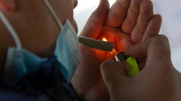 A man smokes a joint at the esplanade of the Estela de Luz monument in Mexico City, on March 10, 2021. Photo by CLAUDIO CRUZ/AFP via Getty Images
