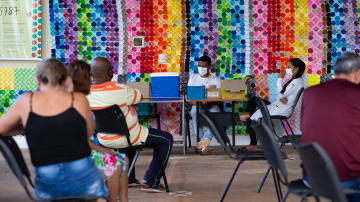 People wait to receive a dose of coronavirus (COVID-19) vaccination in front of the panel in honor of the fatal victims of the disease amidst the coronavirus pandemic in Centro de Saúde 07, on March 29, 2021 in Brasilia Ceilândia, Brazil. Photo by Andressa Anholete / Getty Images