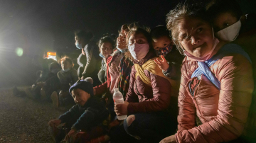 Women and children immigrants who arrived illegally across the Rio Grande river from Mexico rest on March 27, 2021 at a makeshift processing checkpoint before being detained at a holding facility by border patrol agents in the border city of Roma. Photo by Ed JONES / AFP.