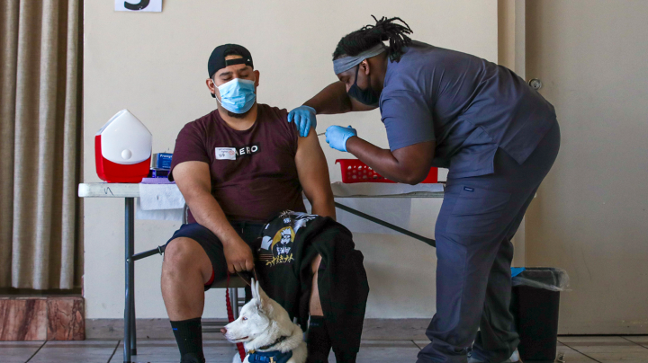 Joel Jurez, 22, holds hid dog Yuki as medical assistant Adrian Davis administers a COVID-19 vaccine at a vaccination clinic established by Councilman Curren Price in partnership with St. John's Well Child and Family Center at St. Patrick's Catholic Church on Friday, April 9, 2021 in Los Angeles, CA. Irfan Khan / Los Angeles Times via Getty Images