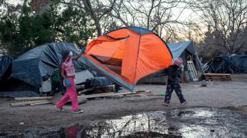 Girls carry a tent to across the campsite of asylum seekers near Bridge of the Americas at Chamizal Park on December 19, 2019 in Ciudad Juarez, Mexico. Photo by PAUL RATJE/AFP via Getty Images