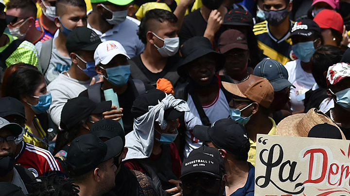People hold a sign reading Democracy is not in quarantine during protest against a tax reform bill they say will leave them poorer as the country battles its deadliest phase yet of the coronavirus pandemic, in Cali, Colombia, on May 1, 2021. Photo by LUIS ROBAYO/AFP via Getty Images