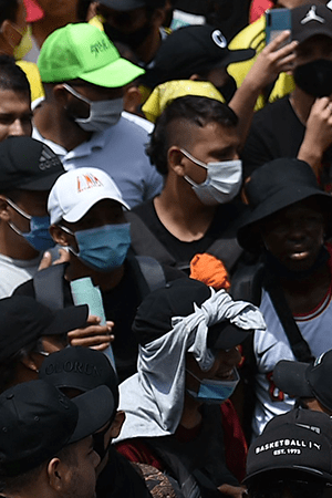 People hold a sign reading Democracy is not in quarantine during protest against a tax reform bill they say will leave them poorer as the country battles its deadliest phase yet of the coronavirus pandemic, in Cali, Colombia, on May 1, 2021. Photo by LUIS ROBAYO/AFP via Getty Images