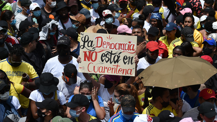 People hold a sign reading Democracy is not in quarantine during protest against a tax reform bill they say will leave them poorer as the country battles its deadliest phase yet of the coronavirus pandemic, in Cali, Colombia, on May 1, 2021. Photo by LUIS ROBAYO/AFP via Getty Images