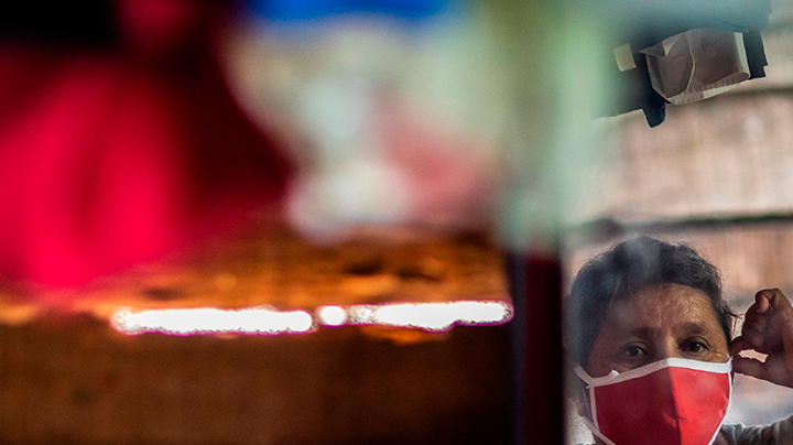 A woman puts on a face mask after recieving food and hygiene kits to face the new Coronavirus (Covid-19) in the City of Jinotega about 150km from Managua on September 17, 2020. Photo by INTI OCON/AFP via Getty Images.