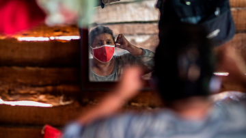 A woman puts on a face mask after recieving food and hygiene kits to face the new Coronavirus (Covid-19) in the City of Jinotega about 150km from Managua on September 17, 2020. Photo by INTI OCON/AFP via Getty Images.