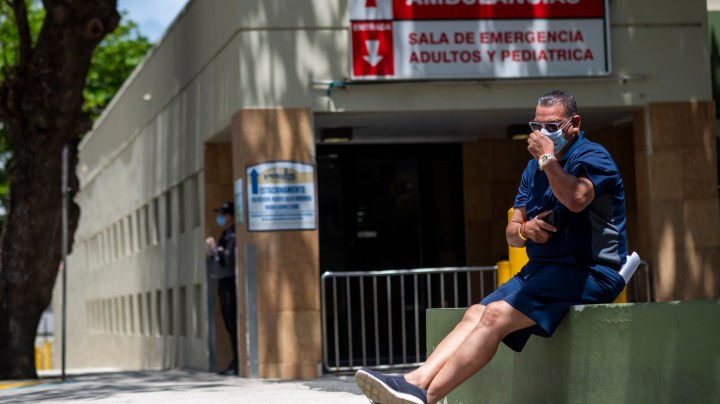 A man wearing a surgical mask sits in front of the emergency room entrance of the Ashford Presbyterian Community Hospital where the first coronavirus patient on the island died earlier in the day in San Juan, Puerto Rico on March 21, 2020. - Almost one billion people were confined to their homes worldwide as the global coronavirus death toll topped 12,000 and US states rolled out stay-at-home measures already imposed across swathes of Europe. More than a third of Americans were adjusting to life in various phases of virtual lockdown -- including in the US's three biggest cities of New York, Los Angeles and Chicago -- with more states expected to ramp up restrictions. (Photo by Ricardo ARDUENGO / AFP) (Photo by RICARDO ARDUENGO/AFP via Getty Images)