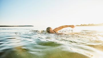 Senior woman swimming in bay on summer evening
