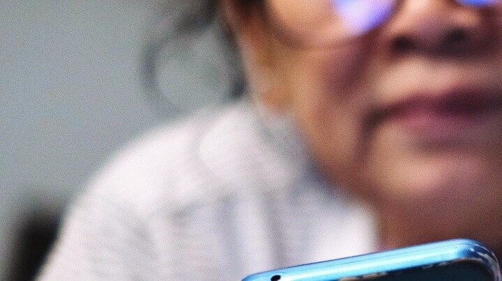 Low Angle View Of Woman Using Phone While Lying On Bed