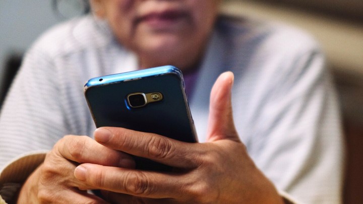 Low Angle View Of Woman Using Phone While Lying On Bed